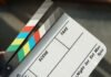 El renacimiento del cine en 70 mm: cuando la gran pantalla vuelve a ser verdaderamente grande A person holding a movie clapper and a pair of scissors