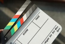El renacimiento del cine en 70 mm: cuando la gran pantalla vuelve a ser verdaderamente grande A person holding a movie clapper and a pair of scissors