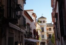 Sevilla conquista el paladar internacional: la cultura del tapeo sevillano que enamora al mundo A narrow city street with a clock tower in the background