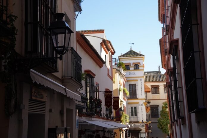 A narrow city street with a clock tower in the background
