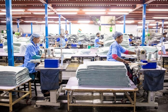 Workers sew textiles in a large factory setting
