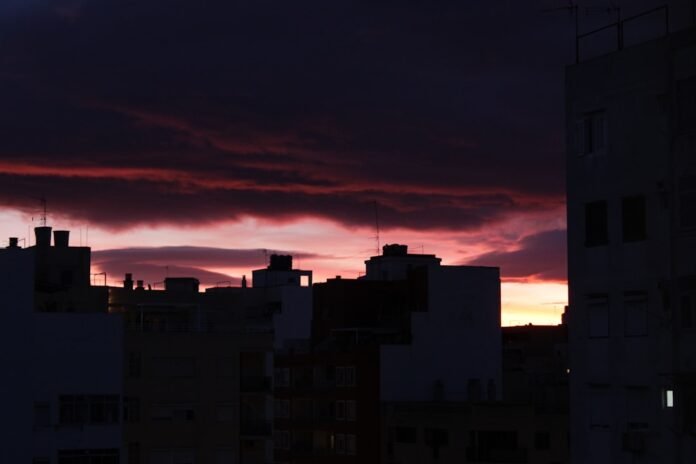 Dark city skyline against a vibrant, dramatic sunset sky
