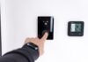 Gestión Inteligente del Consumo Eléctrico: Cómo Ahorrar en tu Factura de la Luz Conociendo las Horas Pico Finger adjusting a modern digital thermostat on wall