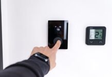 Gestión Inteligente del Consumo Eléctrico: Cómo Ahorrar en tu Factura de la Luz Conociendo las Horas Pico Finger adjusting a modern digital thermostat on wall