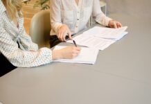 El Nuevo Contrato Laboral: Cuando el Valor Profesional Va Más Allá de las Herramientas que Dominas woman signing on white printer paper beside woman about to touch the documents