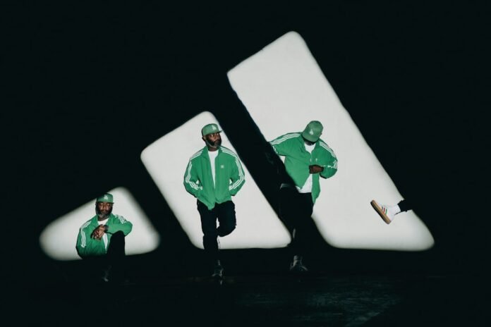 Men pose in front of a giant adidas logo
