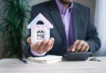 El coste de demonizar la propiedad: cómo una generación perdió la oportunidad de comprar vivienda man holding model house at desk with calculator