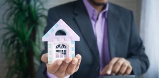 El coste de demonizar la propiedad: cómo una generación perdió la oportunidad de comprar vivienda man holding model house at desk with calculator