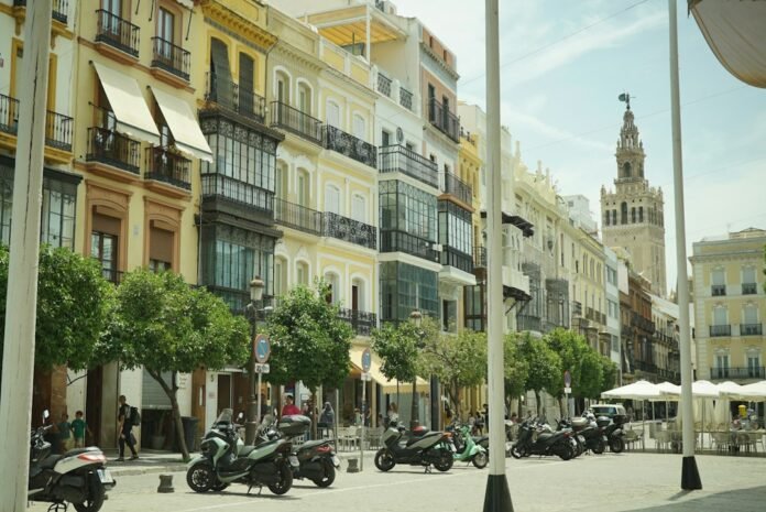 Seville street with historic buildings, parked scooters, and giralda tower