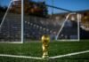 Copa del Rey: La Batalla de los Pequeños Comienza Mientras los Grandes Esperan su Turno A gold trophy on a green soccer field in front of a goal
