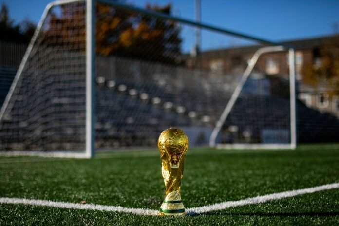 A gold trophy on a green soccer field in front of a goal